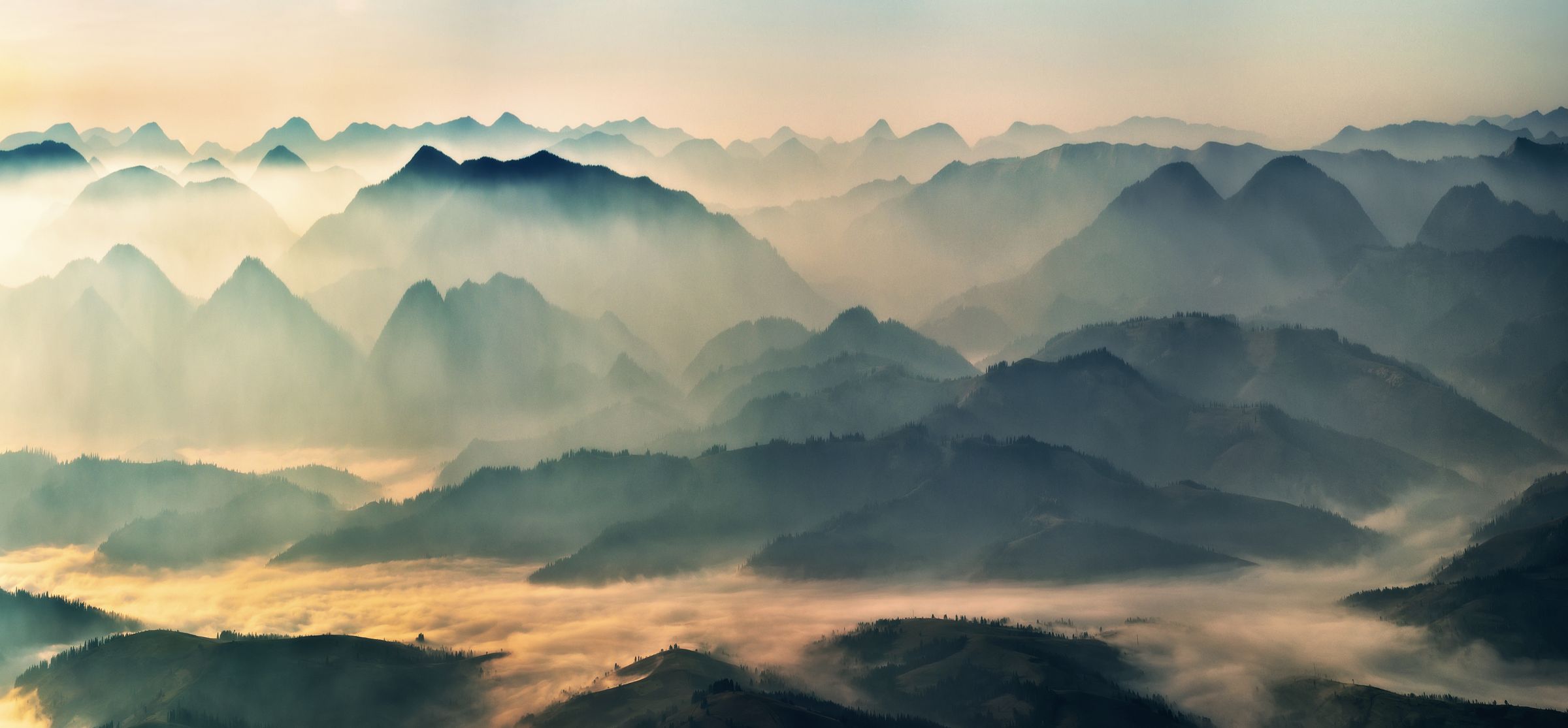 Layer upon layer of misty ridgelines receding into golden dawn light.